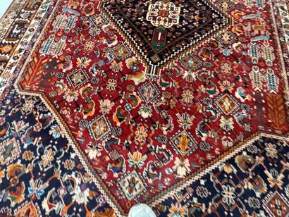 A large hand-knotted wool rug featuring stylized...