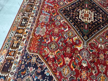 A large hand-knotted wool rug featuring stylized...