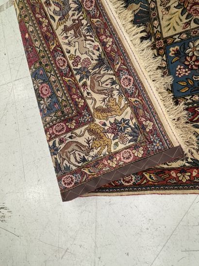 A large hand-knotted wool rug featuring stylized...