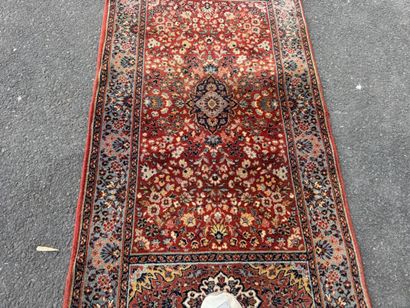 Machine-woven rug with a red background featuring...