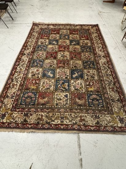 A large hand-knotted wool rug featuring stylized...