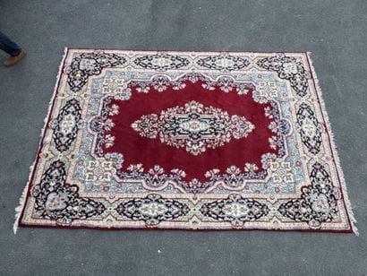 A large hand-knotted wool rug featuring a...
