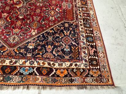 A large hand-knotted wool rug featuring stylized...