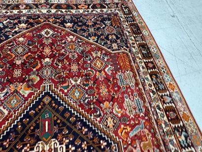 A large hand-knotted wool rug featuring stylized...