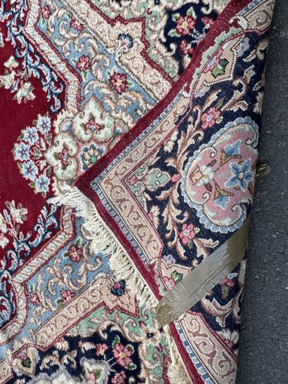 A large hand-knotted wool rug featuring a...