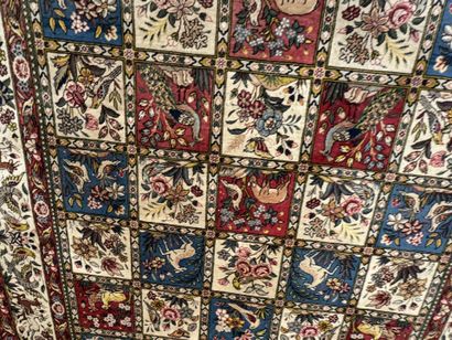 A large hand-knotted wool rug featuring stylized...
