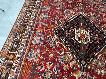 A large hand-knotted wool rug featuring stylized...