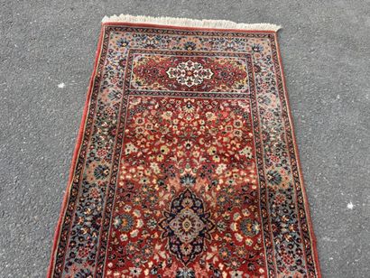 Machine-woven rug with a red background featuring...