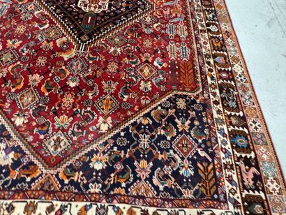A large hand-knotted wool rug featuring stylized...