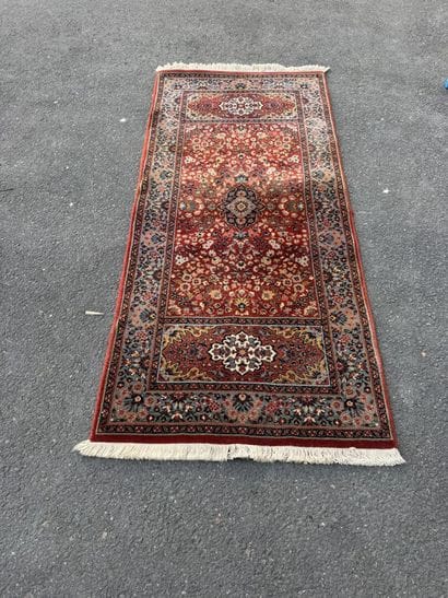 Machine-woven rug with a red background featuring...
