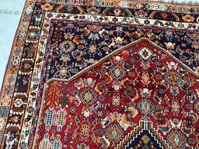 A large hand-knotted wool rug featuring stylized...
