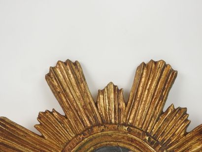 Miroir en bois sculpté doré en forme de soleil.
Travail...