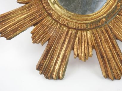 Miroir en bois sculpté doré en forme de soleil.
Travail...
