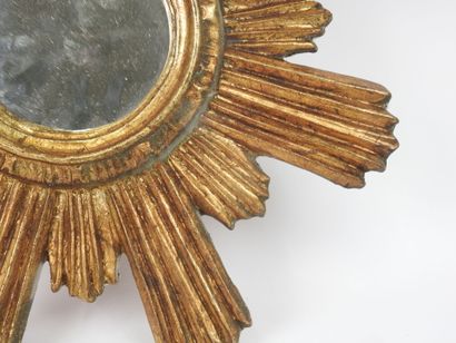 Miroir en bois sculpté doré en forme de soleil.
Travail...