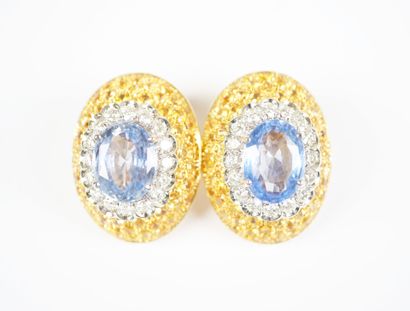 A striking pair of oval ear clips in 18K...
