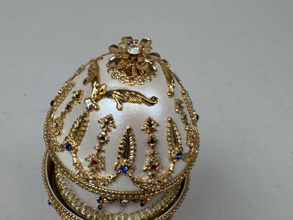 OEuf en métal nacré et doré figurant un manège...