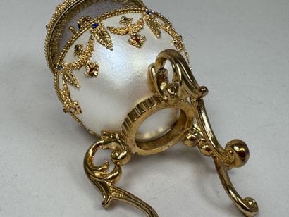 OEuf en métal nacré et doré figurant un manège...