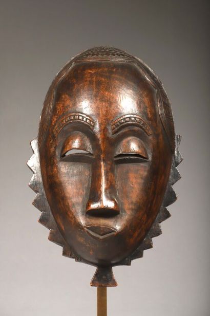 Mask depicting a face encircled by a crenellated...