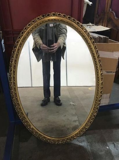 Un miroir en bois doré, de forme ovale. Style...