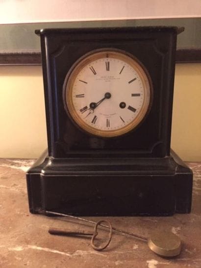 Une pendule borne en marbre noir, le cadran...