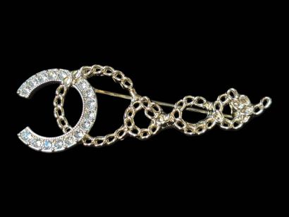 CHANEL
Brooch in gilt metal and white rhinestones...