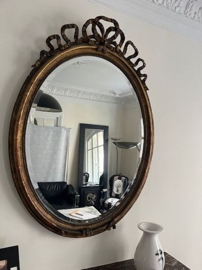 Miroir en bois et stuc doré de forme ovale,
Style...