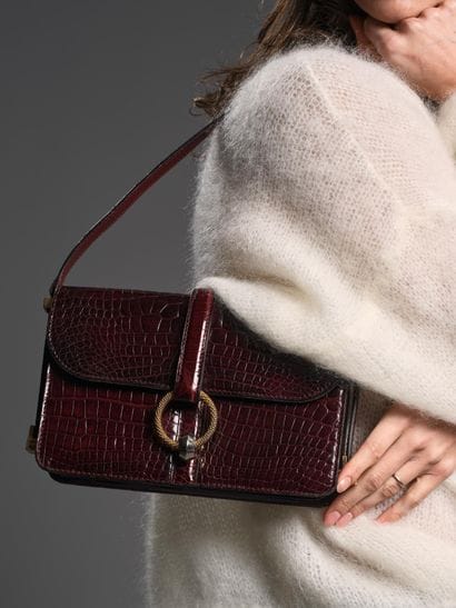 Brown crocodile-style leather handbag.
Twisted...