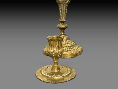 A pair of chiseled bronze candlesticks decorated...
