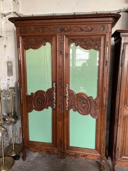 A carved wood cabinet decorated with draperies,...