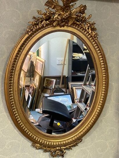 Miroir ovale en bois doré, fronton à décor...