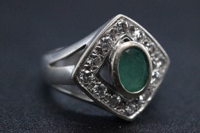 White gold ring set with a green stone in...