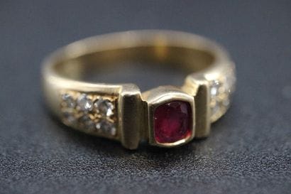 Yellow gold ring set with a red stone and...