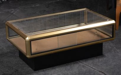 Table basse vitrine en laiton et verre. 40...