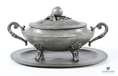 A pewter oval soup tureen and its base, flanked...