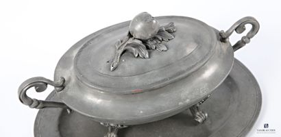 A pewter oval soup tureen and its base, flanked...
