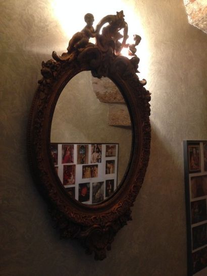 Petit miroir ovale en bois doré orné de putti...