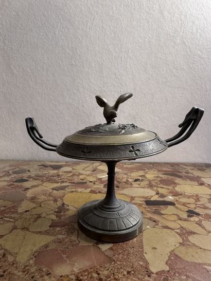 A small bronze cup with a lid; the lid's...