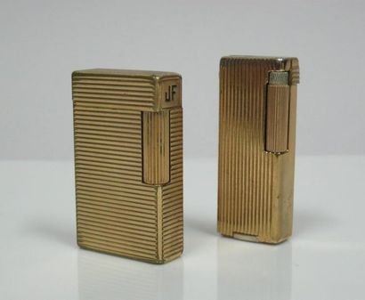 Deux briquets en métal doré rainuré. L'un...