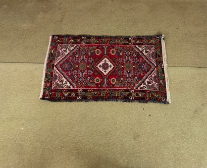 Rectangular knotted wool rug with a red background,...