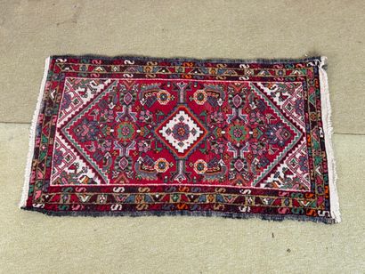Rectangular knotted wool rug with a red background,...