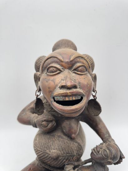 SEATED FEMALE FIGURE HOLDING A STATUETTE
Mid-20th...