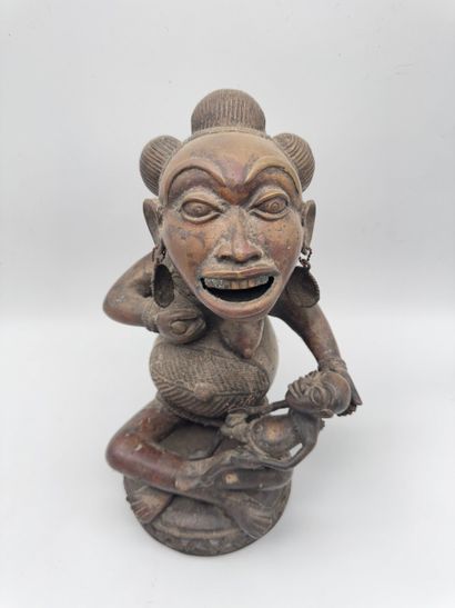 SEATED FEMALE FIGURE HOLDING A STATUETTE
Mid-20th...