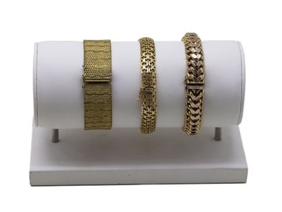 Trois bracelets articulés en métal doré,...