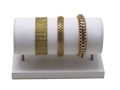 Trois bracelets articulés en métal doré,...