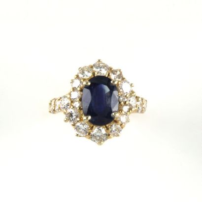 Bague en por jaune ornée d'un saphir entouré...