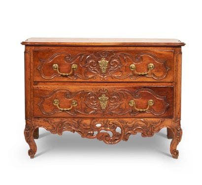A walnut chest of drawers, molded and carved,...