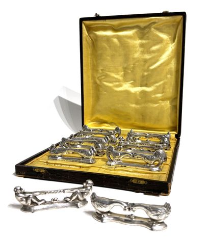 TWELVE SILVER-METAL HOLDERS, each formed...