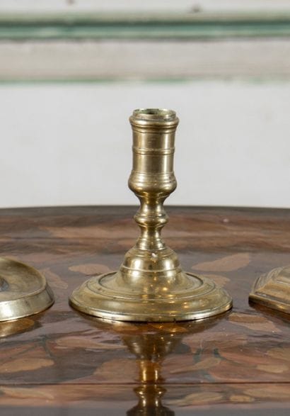 Small brass candlestick with high tap resting...