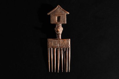 Yaka-style wooden comb topped with a face...