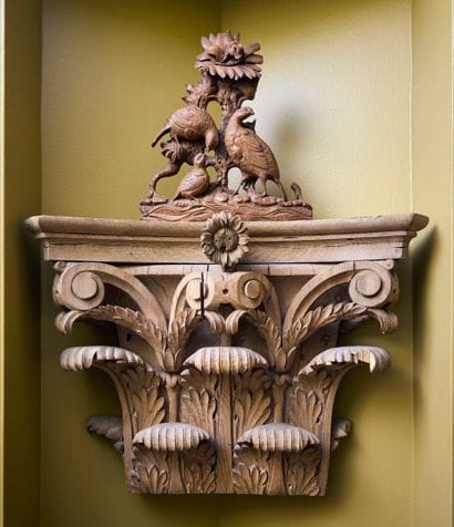 Carved wood sconce forming a capital with...